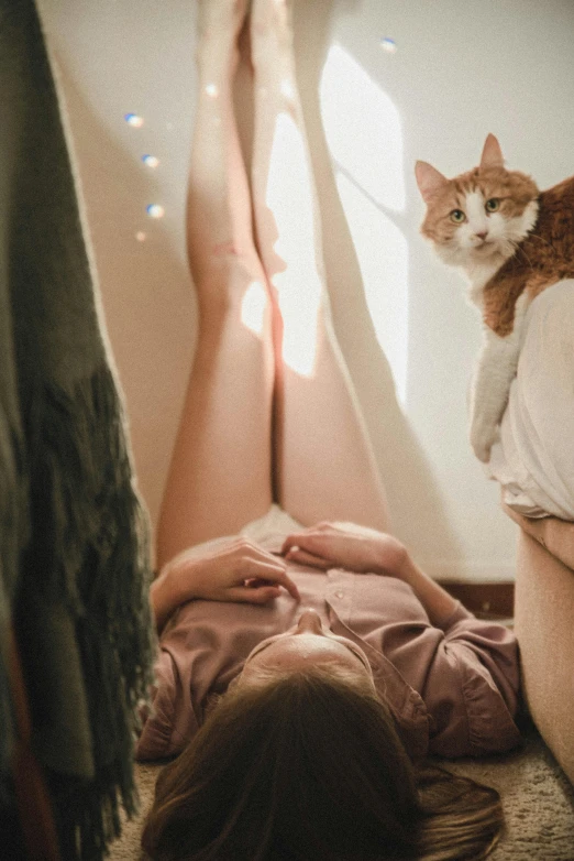 a woman laying in bed with her legs over the head of a cat