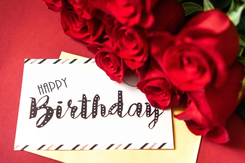 a happy birthday card with red roses and a paper