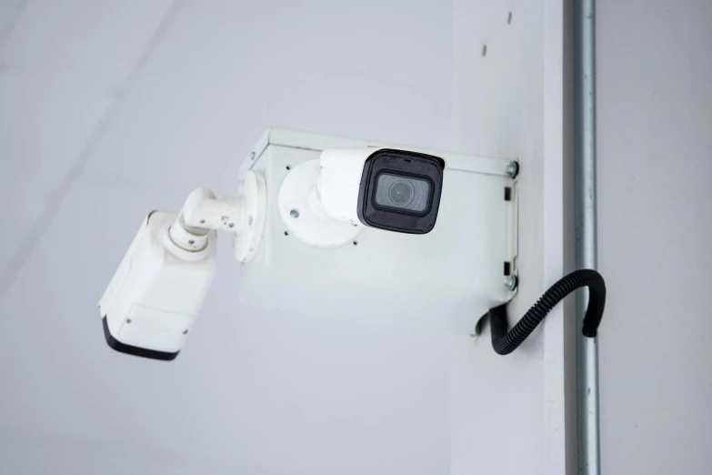 security camera mounted to side of white building with gray door