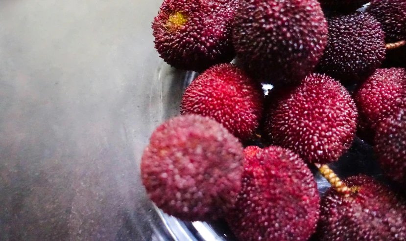 a bowl filled with red fruit sitting on top of a wooden table