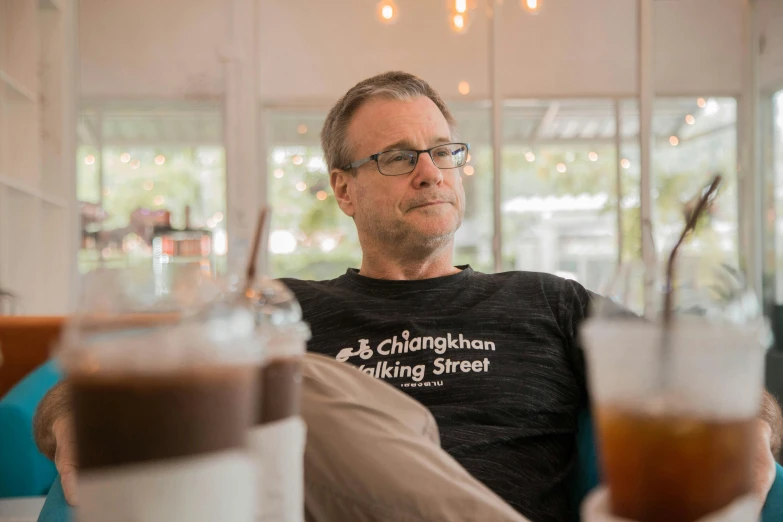 a man wearing glasses looking down in the glass