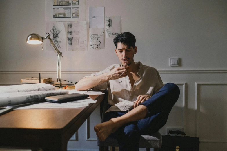 man sitting in chair with papers on desk with lamp