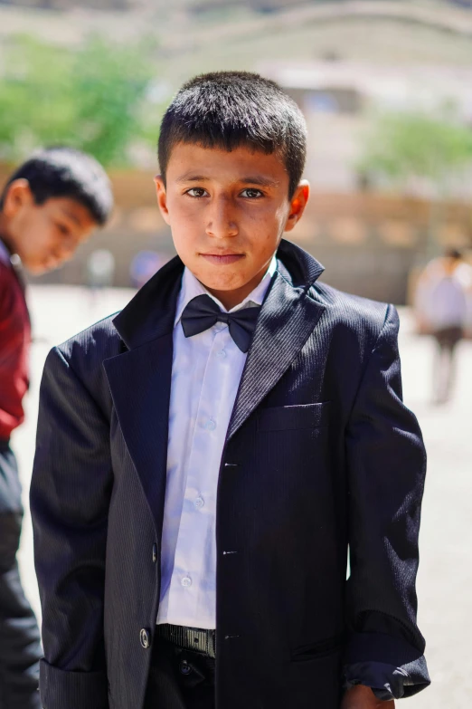 an individual poses for the camera while wearing a dress shirt, vest and bow tie