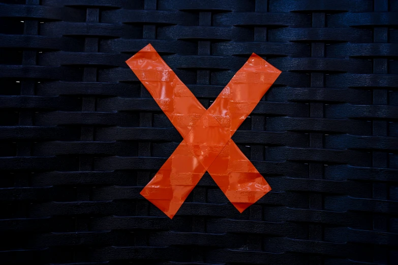 a po of the letter x made up of orange ribbon pieces
