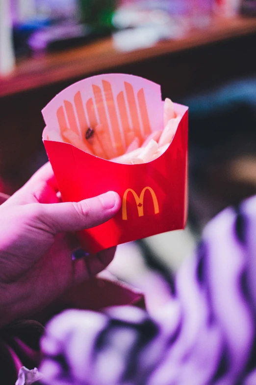 a paper box with fries inside is pictured