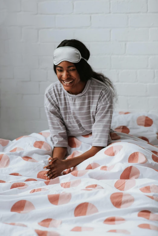 the girl is in bed smiling with her head resting on a pillow