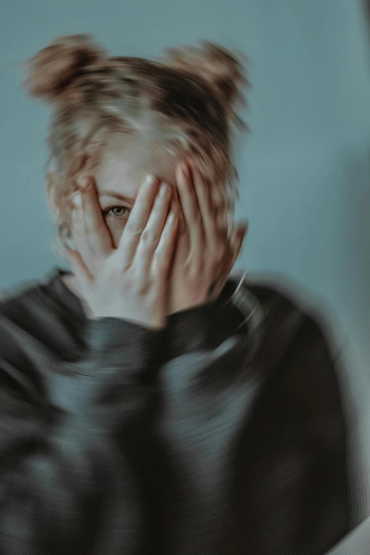 woman in black sweatshirt covering her eyes with hands