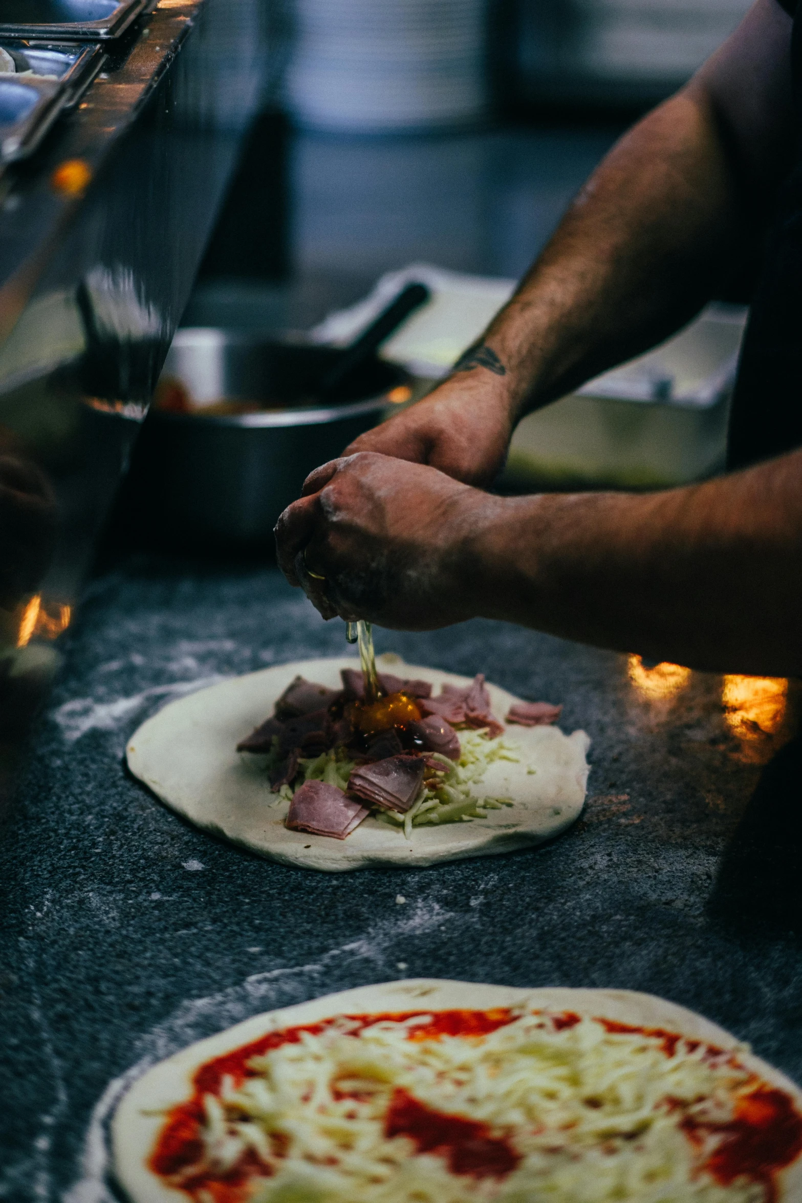 a person with pizza crusts and another person slicing them