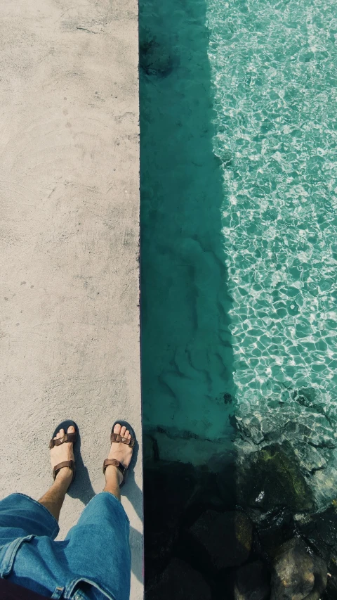 a pair of feet standing next to a body of water