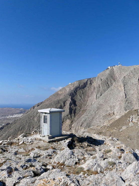 a portable toilet on top of a rock covered hill