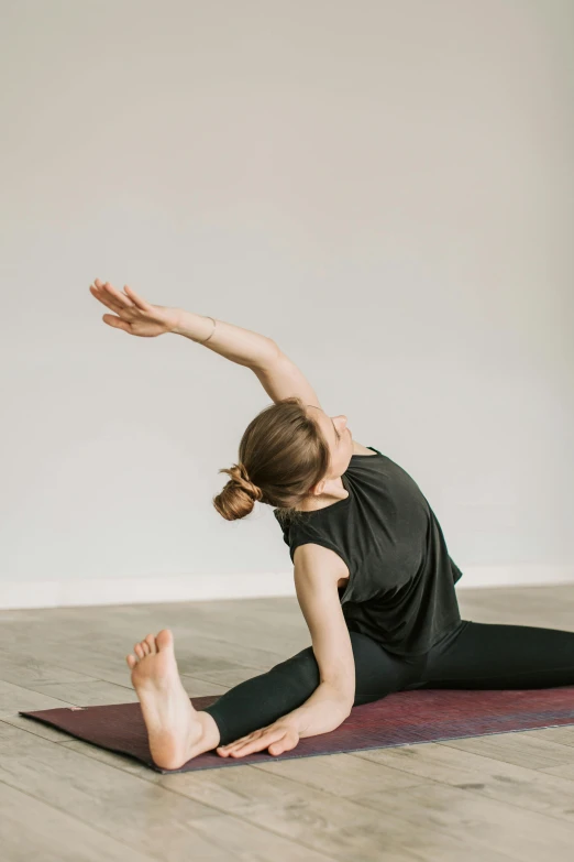 a woman in a black top doing yoga on a yoga mat