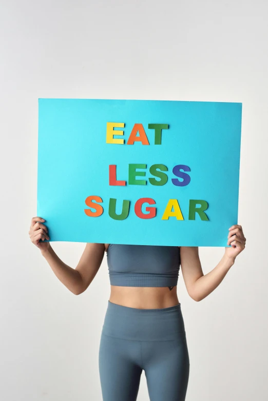 a young woman holding a sign reading eat less sugar