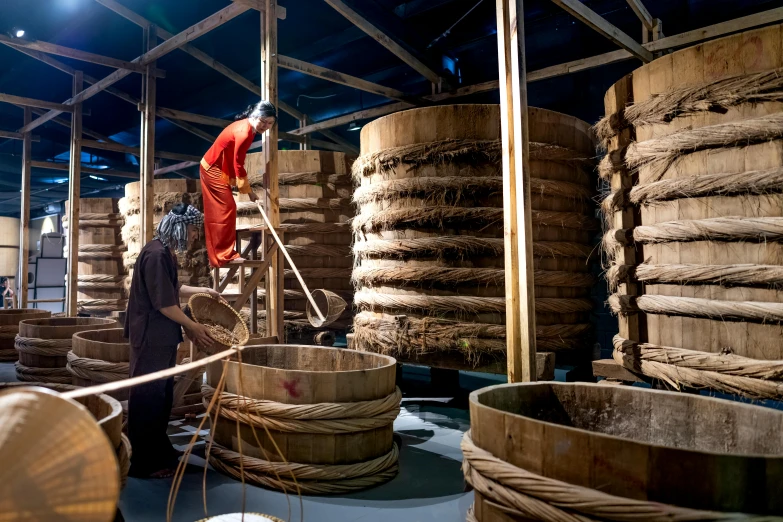 two people near some barrels of wood