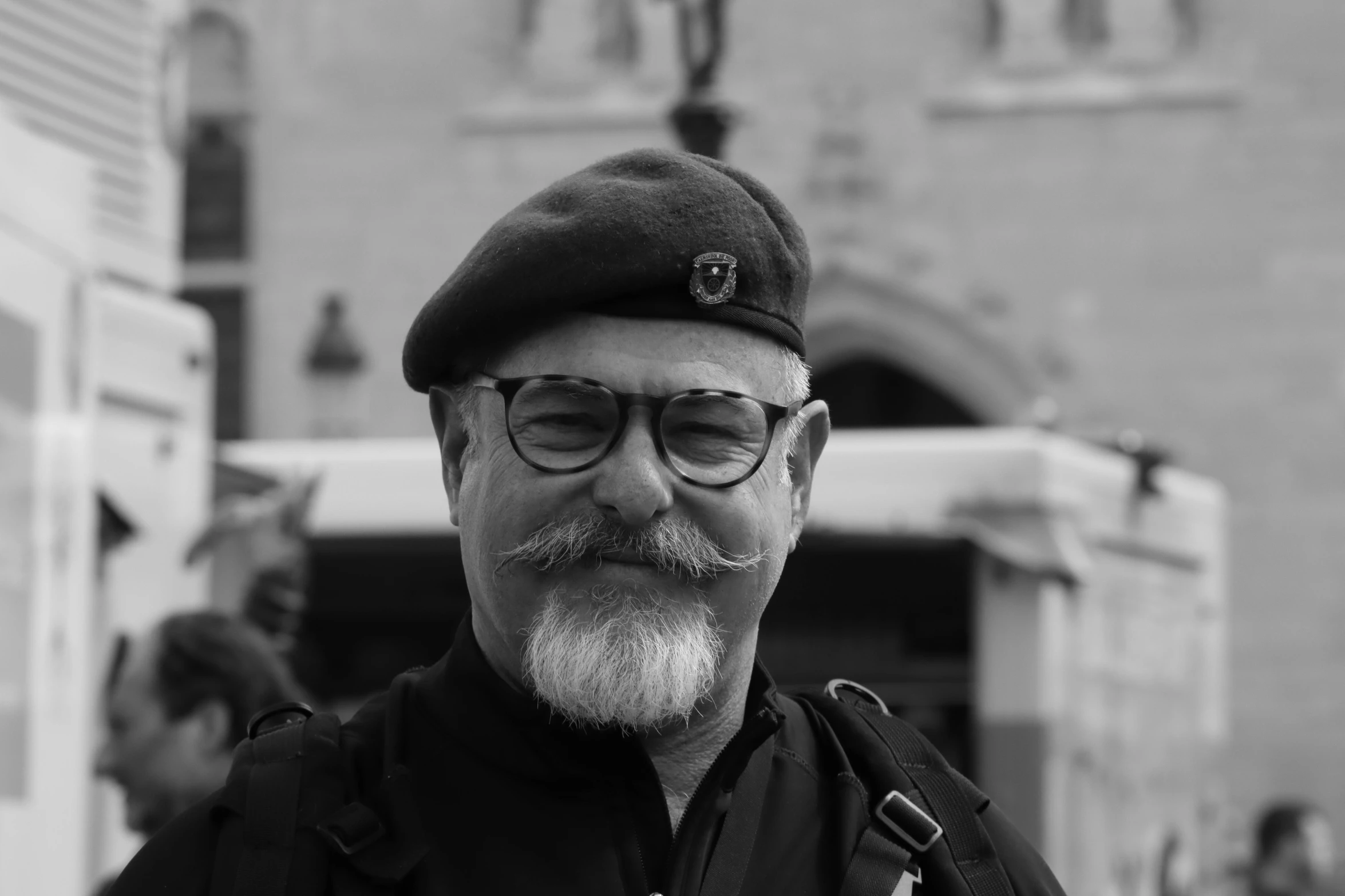 man with white beard and glasses on wearing a hat and a backpack
