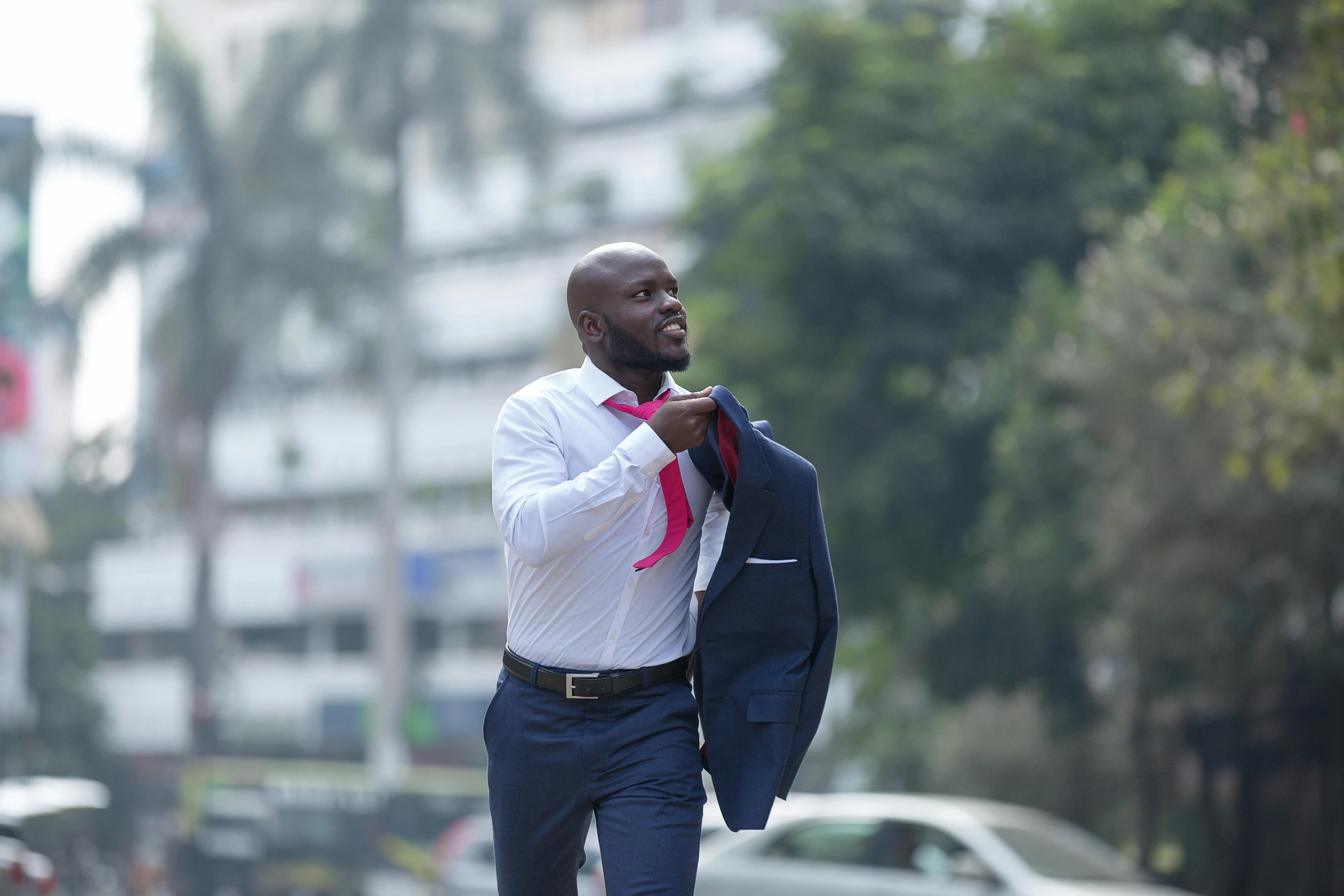 a man walking down the street tying a tie