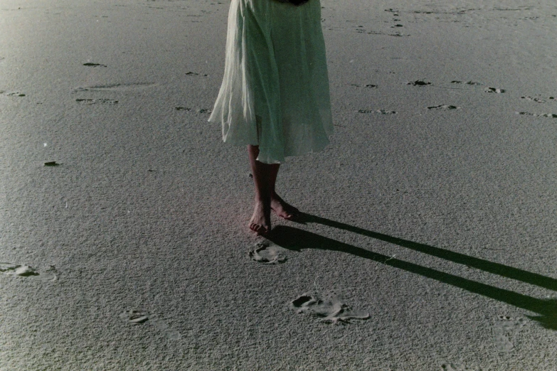 a woman in a dress walking along the beach