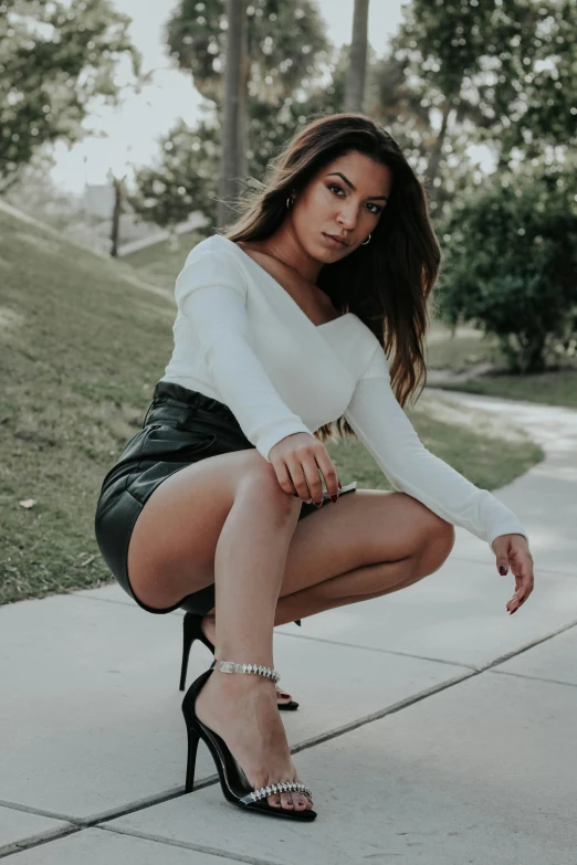 a woman sitting on the ground next to a sidewalk