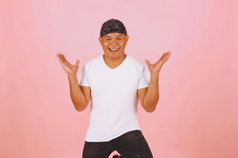 man in white shirt with pink background showing ok sign
