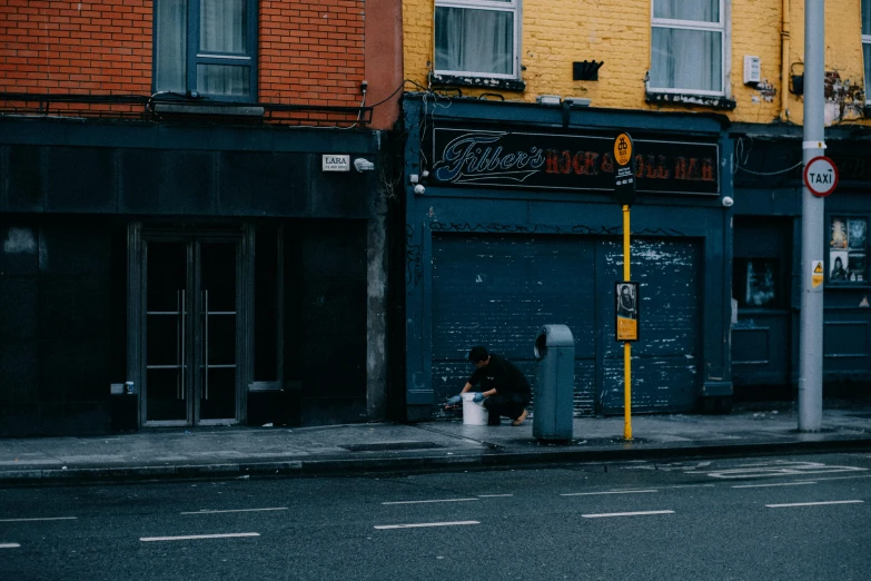 a person sitting on the curb of a city street