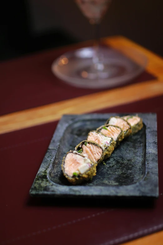 a square plate on the table has salmon in a couscous