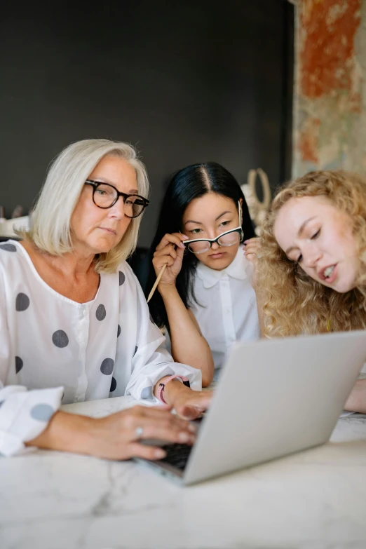 three woman work on a laptop together