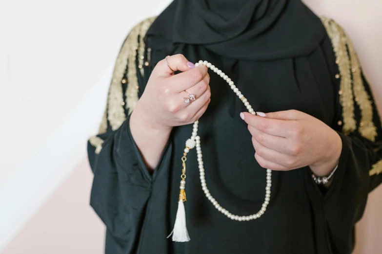 a woman is tying beads on her black outfit