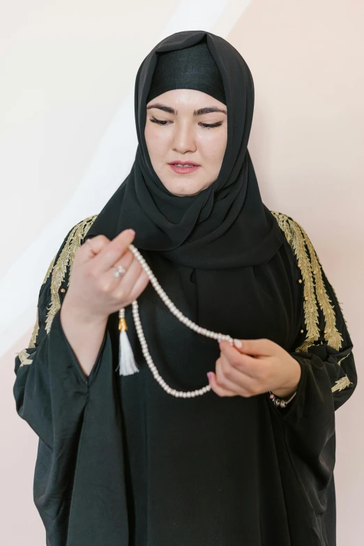 a woman wearing black clothing is putting on some beads