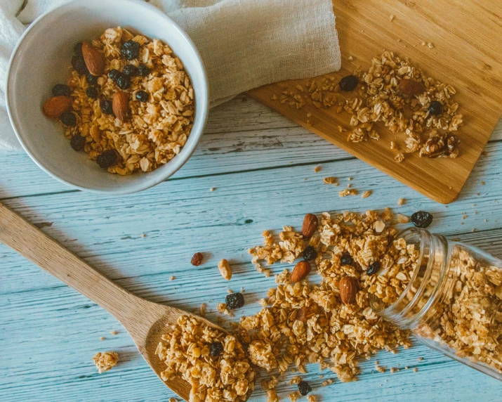 cereal in a white bowl next to a wooden spoon on a blue surface