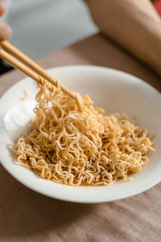 someone holding chopsticks over the noodles in a bowl