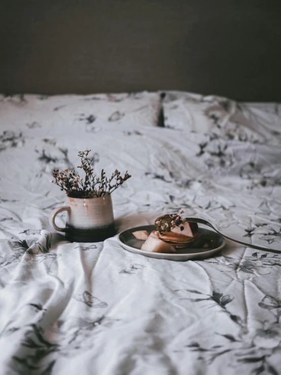 two desserts sitting on top of a bed next to a mug