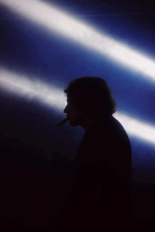 the person is silhouetted against blue lights