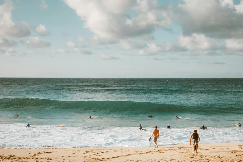 two people walking in the sand on the beach near the water