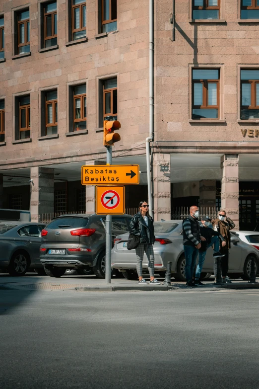 a group of men standing on the corner by a street sign