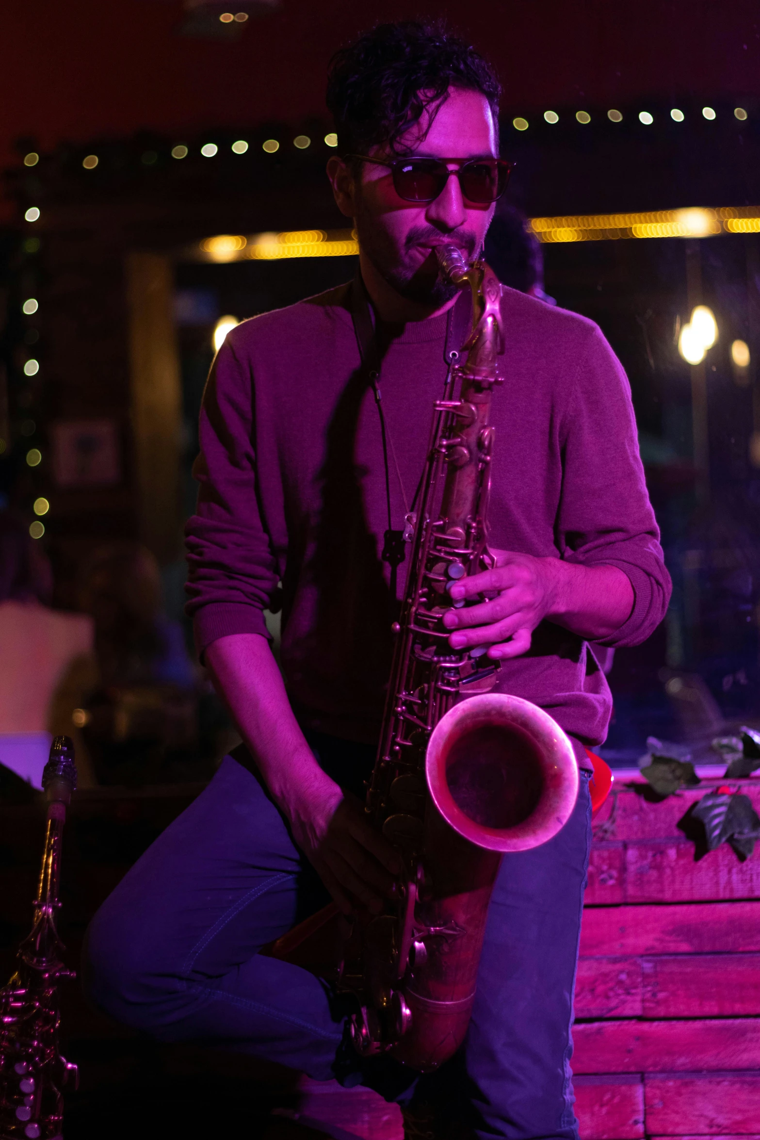 a man with glasses sitting down playing a saxophone