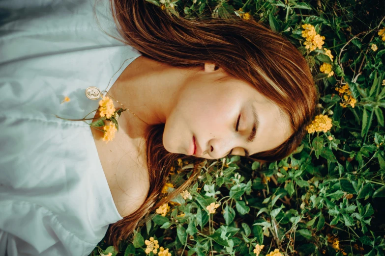 a young woman is laying down in a field of flowers