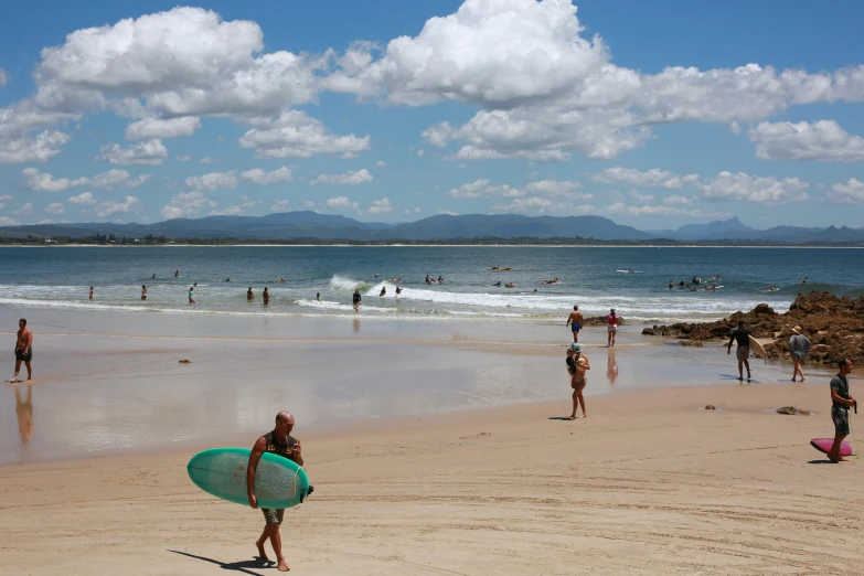 surfers are lined up at the beach on the sunny day