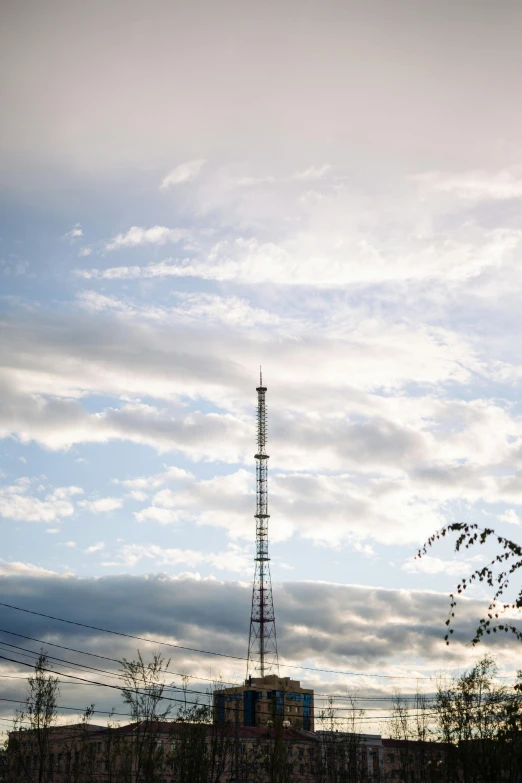 a tall television tower surrounded by trees on a cloudy day