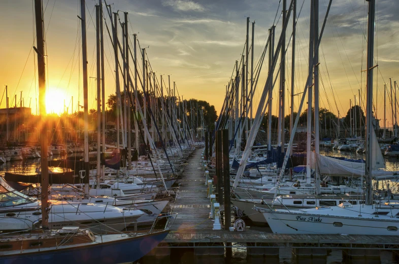 the sun setting over several boats in the harbor