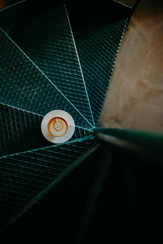 there is a cup of coffee on the top of this spiral staircase