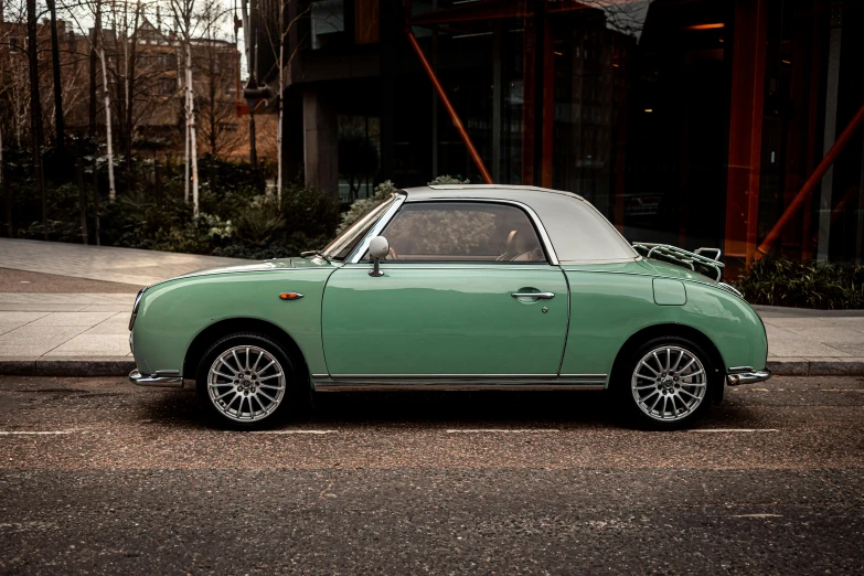 the green car is parked in front of a building