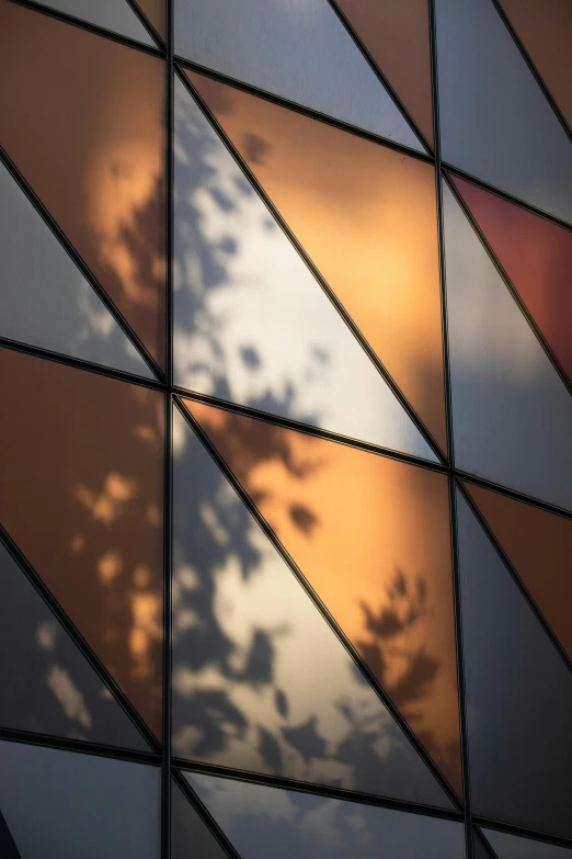 the side of a building with a reflection of clouds and clouds in it