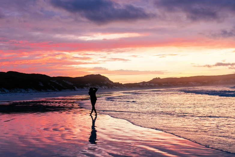 a person standing on the beach at sunset