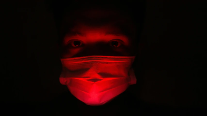 a person with a mask is illuminated in the dark