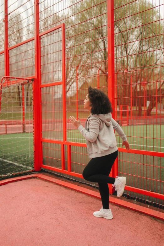 a woman jumping up in the air in front of a fence