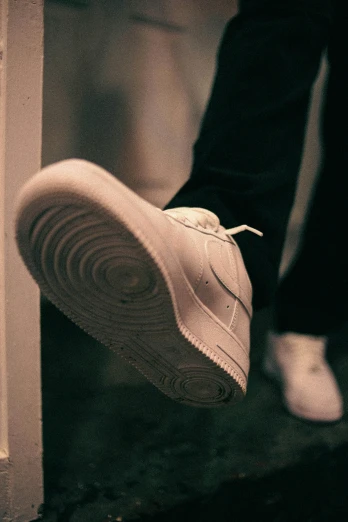 a man wearing white tennis shoes as if in a dark alley