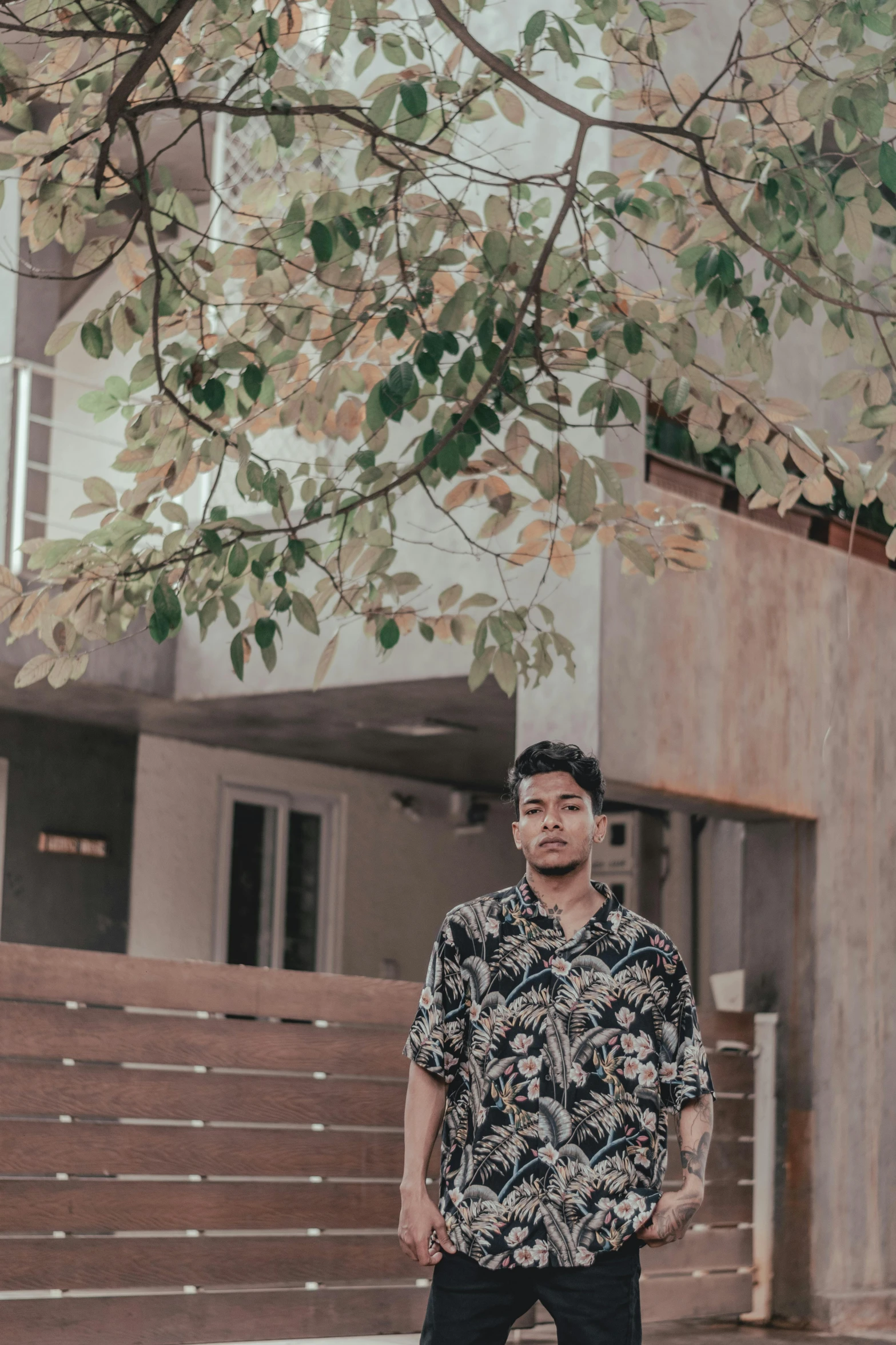 man wearing hawaiian shirt posing in front of tree