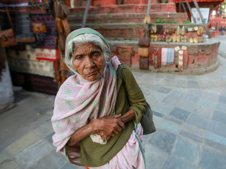 the old woman in green shirt and head scarf standing on the street