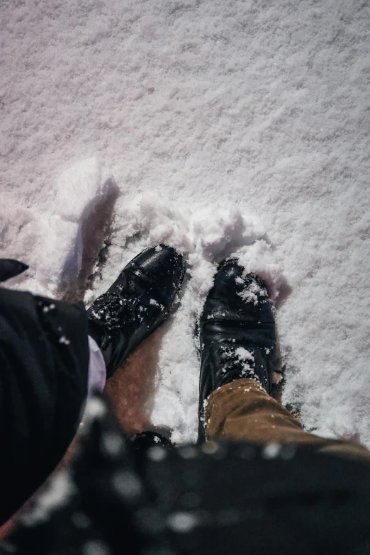 a person's feet in snow with black snow shoes