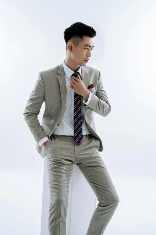 a man wearing a suit and tie standing in front of a white backdrop