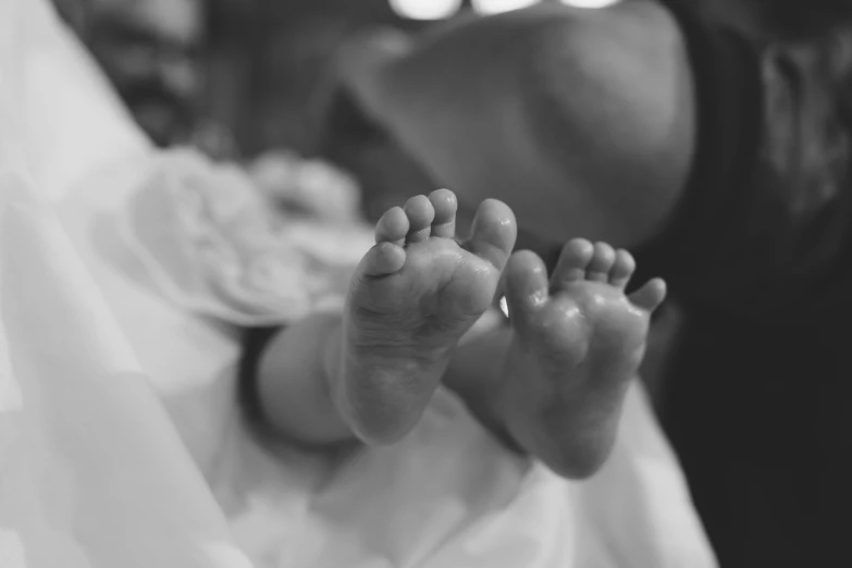 a black and white po of an infant's feet in a white dress